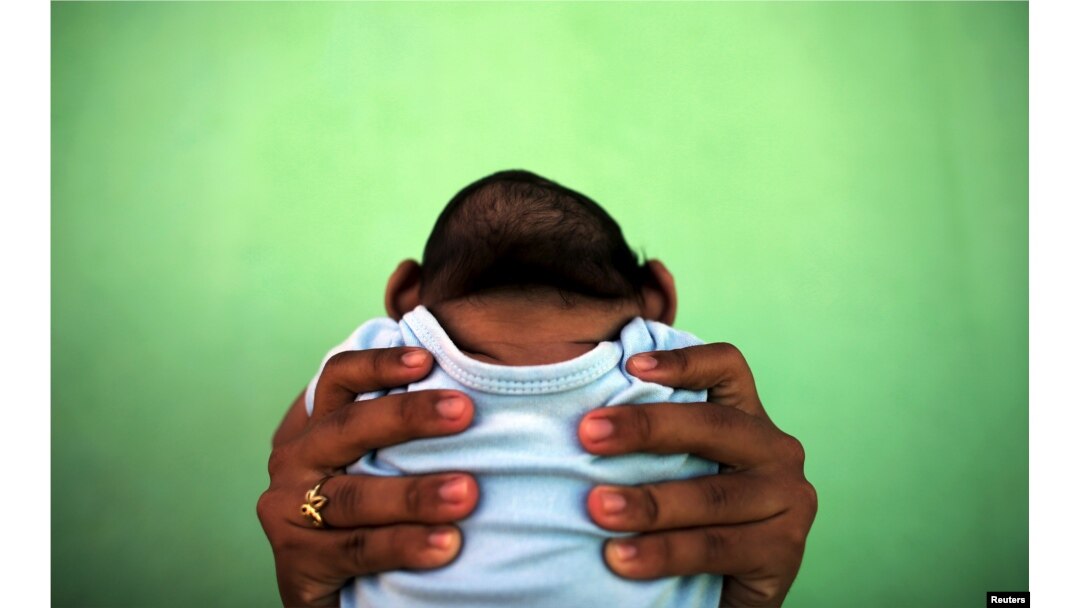 FILE - Jackeline, 26, holds her son who is 4-months old and born with microcephaly, in front of their house in Olinda, near Recife, Brazil, February 11, 2016.