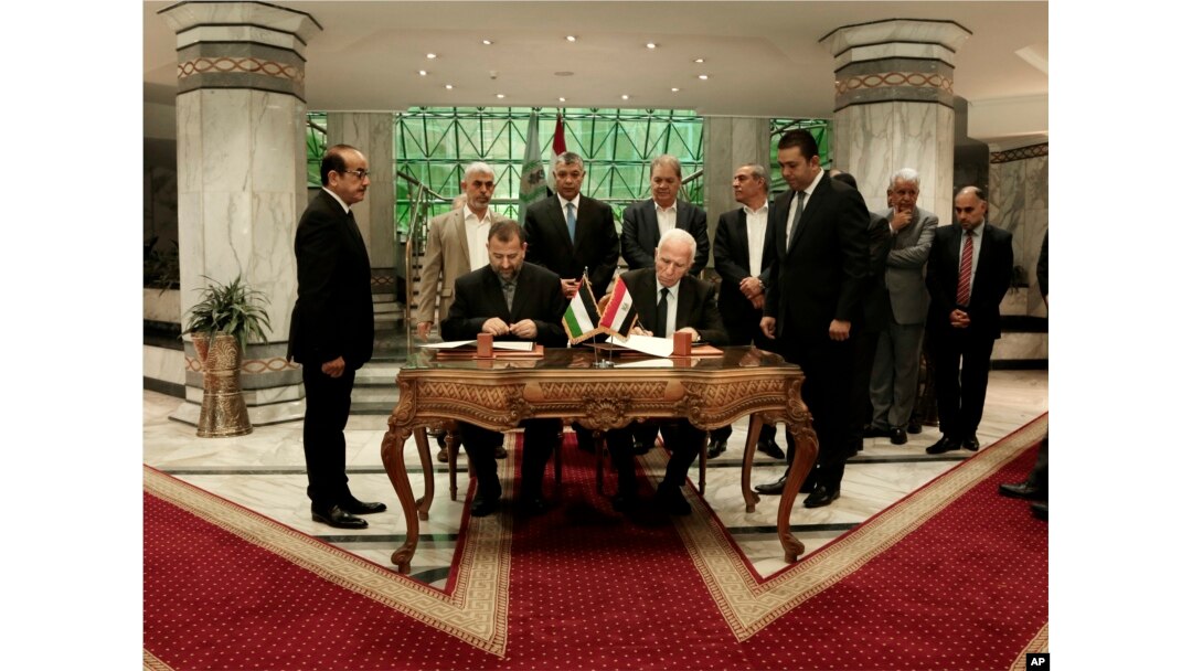 FILE - Senior Fatah official Azzam al-Ahmad, center right, and Hamas' representative, Saleh al-Arouri, center left, sign a reconciliation deal during a short ceremony at the Egyptian intelligence complex in Cairo, Egypt, Oct. 12, 2017.
