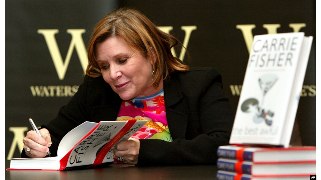 FILE - In this Feb. 20, 2004, photo, "Star Wars" actress, humorist and author Carrie Fisher autographs her book "The Best Awful" at a promotional event in London.