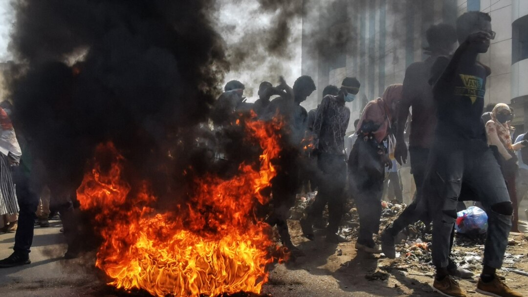 Sudanese protesters rallying against the military walk past burning tires in Khartoum, Jan. 6, 2022. The protests followed the resignation of civilian Prime Minister Abdalla Hamdok this week, which left the military fully in charge.