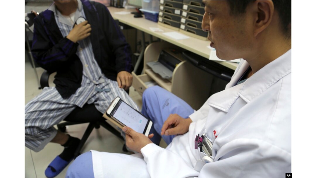 Dr. Li Dianyou uses a tablet computer to adjust the settings of a deep brain stimulation device implanted in the brain of a methamphetamine user named Yan, left, on Monday, Oct. 29, 2018, at Ruijin Hospital in Shanghai, China.