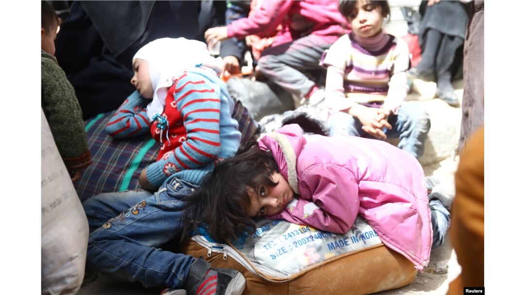 A girl looks at the camera during evacuations from eastern Ghouta, near Damascus, Syria.