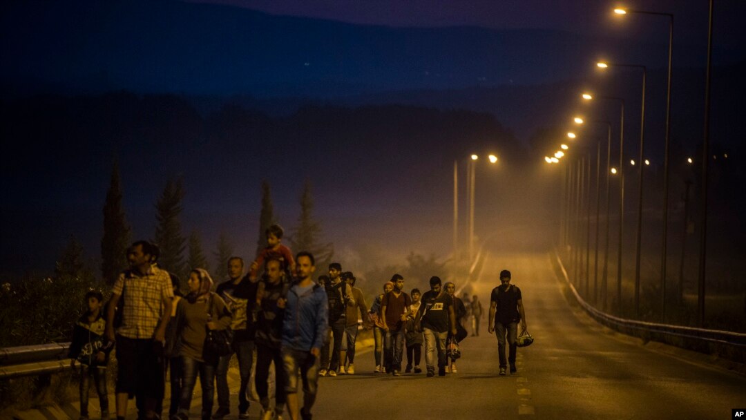 Syrian refugees walk along a road of the border town of Idomeni , northern Greece, to cross the border and enter Macedonia, Aug. 25, 2015.