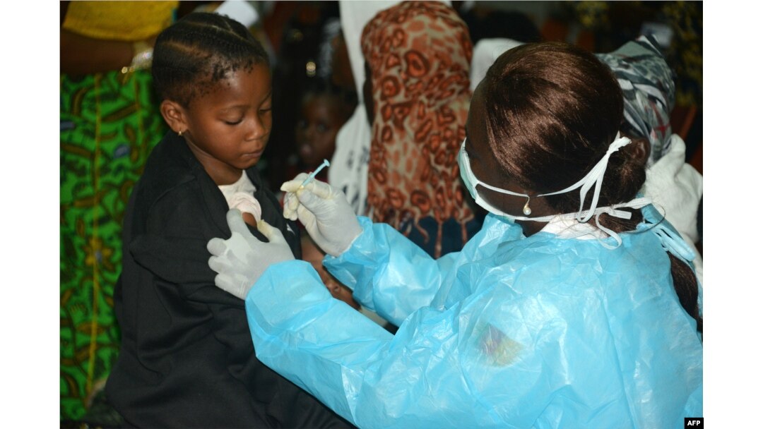 FILE - A Cameroonian nurse gives an injection to a girl arriving with her familly after spending several months in Libya, at the Yaounde International Airport in Cameroon, Nov. 22, 2017.