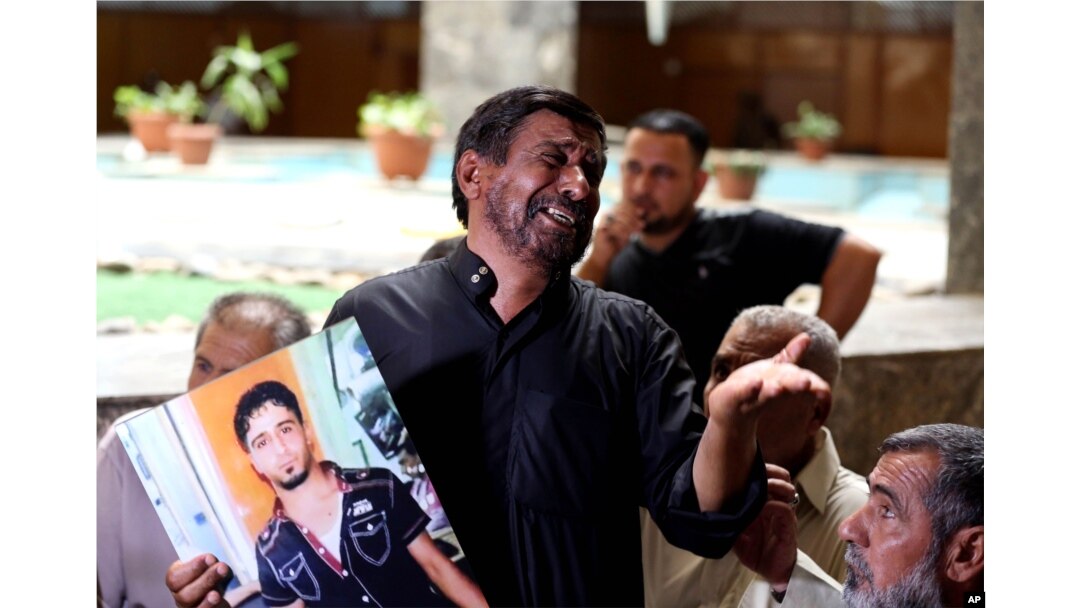 FILE - A grieving Iraqi father shows a poster of his dead son, who was an Iraqi soldier, in a Baghdad courtroom, July 8, 2014.
