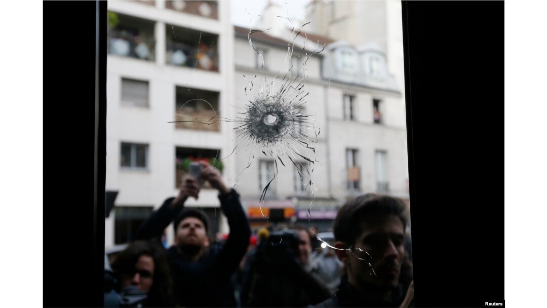 Journalists work outside a restaurant where bullet impacts are seen the day after a series of deadly attacks in Paris, France, Nov. 14, 2015.