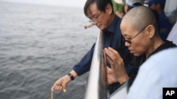 FILE - In this photo provided by the Shenyang Municipal Information Office, Liu Xia, the wife of Chinese Nobel Peace Prize laureate Liu Xiaobo, watches as Liu's ashes are buried at sea, July 15, 2017.