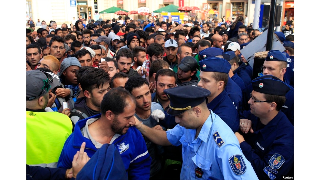 Migrants discuss with a policeman as they wait for trains at Keleti railway station in Budapest, Hungary, Sept. 8, 2015.