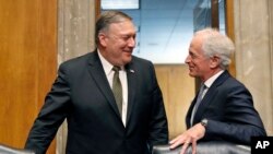 El nominado para secretario de Estado Mike Pompeo, (izquierda) conversa con Bob Corker, republicano por Tennessee, presidente de la Comisión de Relaciones Exteriores del Seando, durante una audiencia de confirmación el 12 de abril, de 2018.