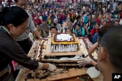 Exile Tibetans wait for a cake to be distributed as they mark the 82nd birthday of their spiritual leader the Dalai Lama in Dharmsala, India, July 6, 2017. In a public event attended by hundreds, Tibetans danced, distributed sweets and offered their respects in front of a portrait of their leader.