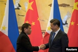 FILE - Philippine President Rodrigo Duterte (L) and Chinese President Xi Jinping shake hands after a signing ceremony held in Beijing, Oct. 20, 2016.