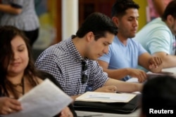 FILE - Ernesto Delgado, center, a Deferred Action for Childhood Arrivals recipient, fills out his renewal application during the immigration ministry at Lincoln Methodist Church in Chicago, Sept. 10, 2017.
