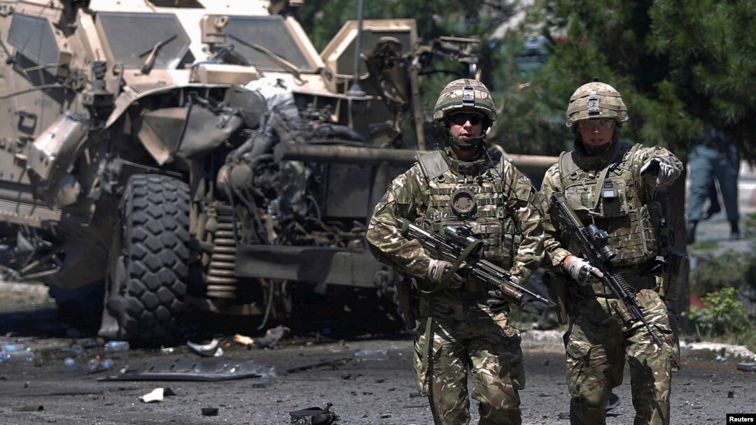 FILE - NATO soldiers walk at the site of a suicide bomb attack in Kabul, Afghanistan, June 30, 2015.