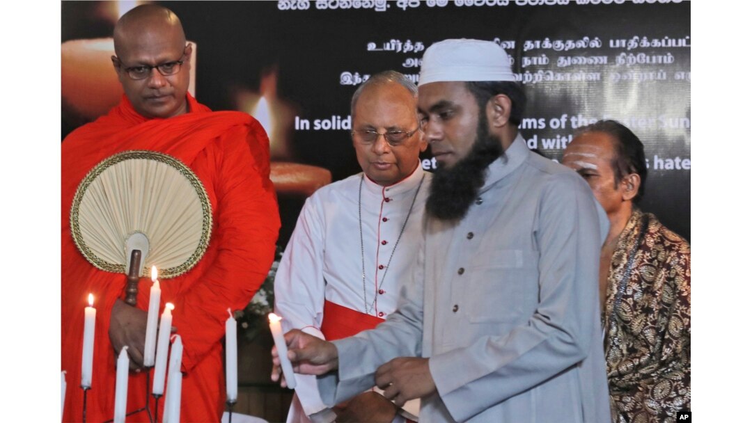 A Sri Lankan Muslim priest, lights a candle as Buddhist priest, left, Hindu priest, right, and Christian archbishop, center, watch during a function to express solidarity with all the victims of Easter Sunday attacks, in Colombo, April 28, 2019.