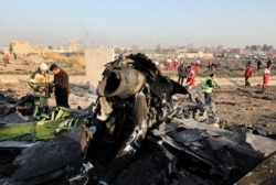 FILE - Debris is seen from an Ukrainian plane which crashed as authorities work at the scene in Shahedshahr, southwest of the capital Tehran, Iran, Jan. 8, 2020.