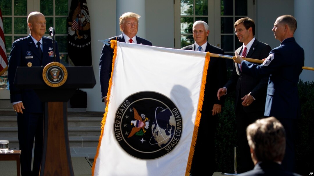 FILE- Gen. John "Jay" Raymond, President Trump, Vice President Pence, and Sec. of Defense Mark Esper, unfurl the U.S. Space Command flag during a ceremony to establishment of the U.S. Space Command in the Rose Garden of the White House, Aug. 29, 2019.