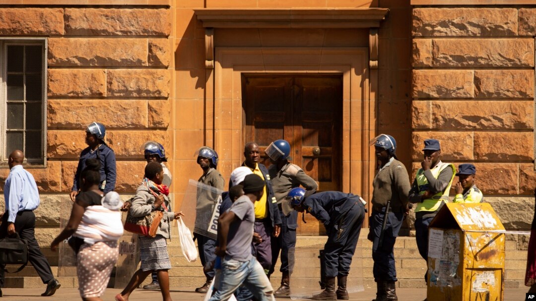 Policemen keep an eye on pedestrians passing by, in Bulawayo, Zimbabwe, Monday, Aug. 19, 2019. Few people turned up for an opposition protest Monday in the Zimbabwe's second city as armed police maintained a heavy presence on the streets. (AP Photo…