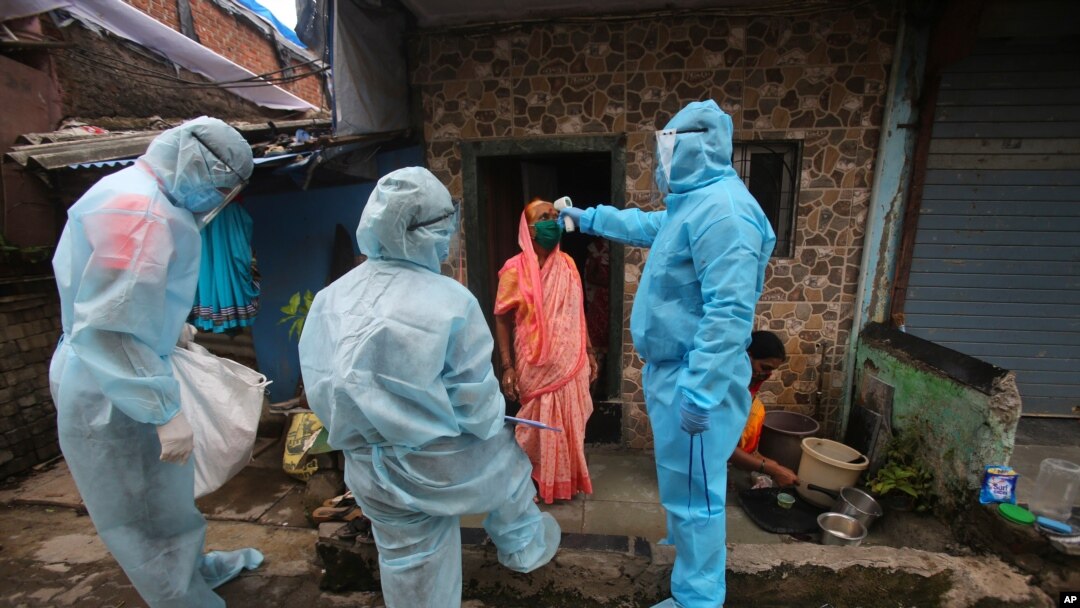 A health worker wearing personal protective equipment checks the temperature of a woman at a slum in Mumbai, India, June 17, 2020. 