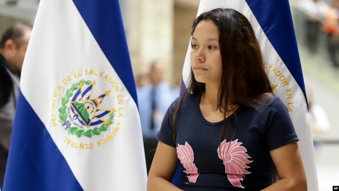 Tania Vanessa Avalos se detiene cerca de donde un miembro del gobierno da una conferencia de prensa después de su llegada a San Salvador, El Salvador, el jueves 28 de junio de 2019. Ella es la esposa del hombre que se ahogó junto con su hija de 23 meses tratando de cruzar Río Bra