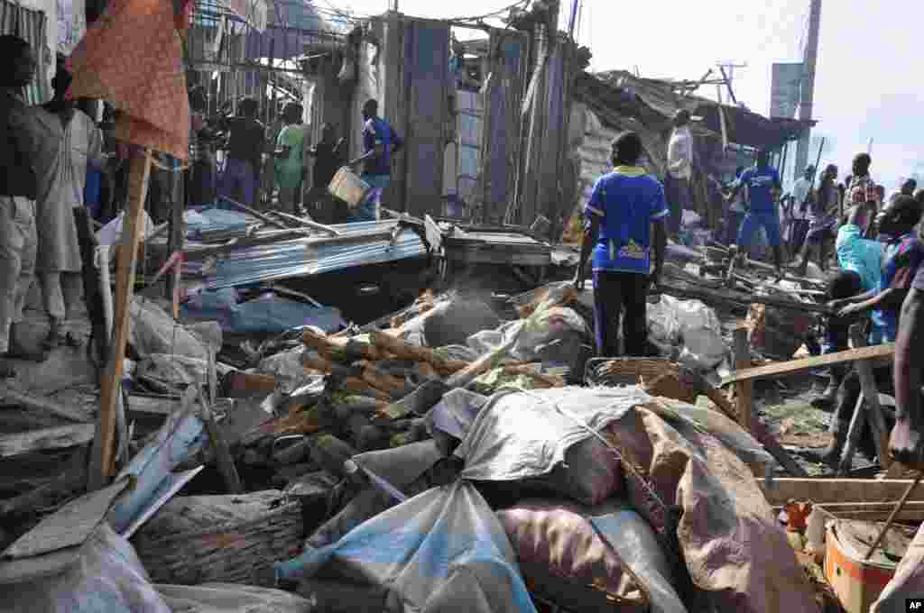 Mutane sun taru kusa da inda bam ya tashi cikin mota a kasuwar "Monday Market" ta Maiduguri, talata 1 Yuli, 2014. Mutane da dama sun mutu, akasarinsu mata tsoffi da almajirai dake bara.