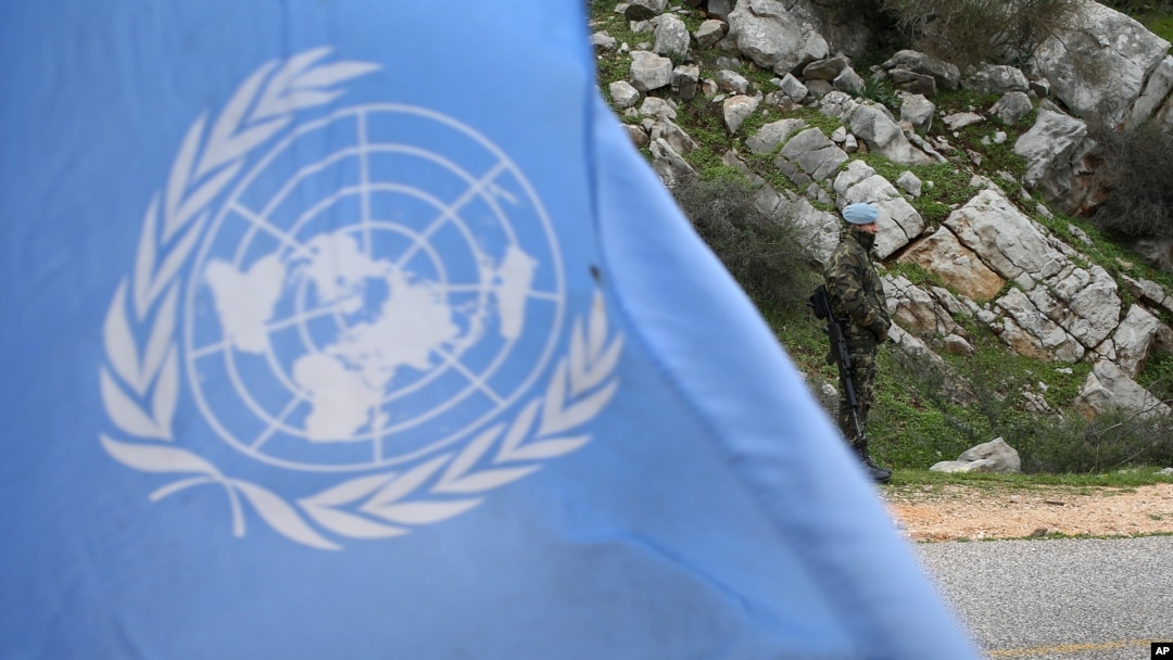 FILE - A United Nations peacekeeper is seen standing behind a U.N. flag.
