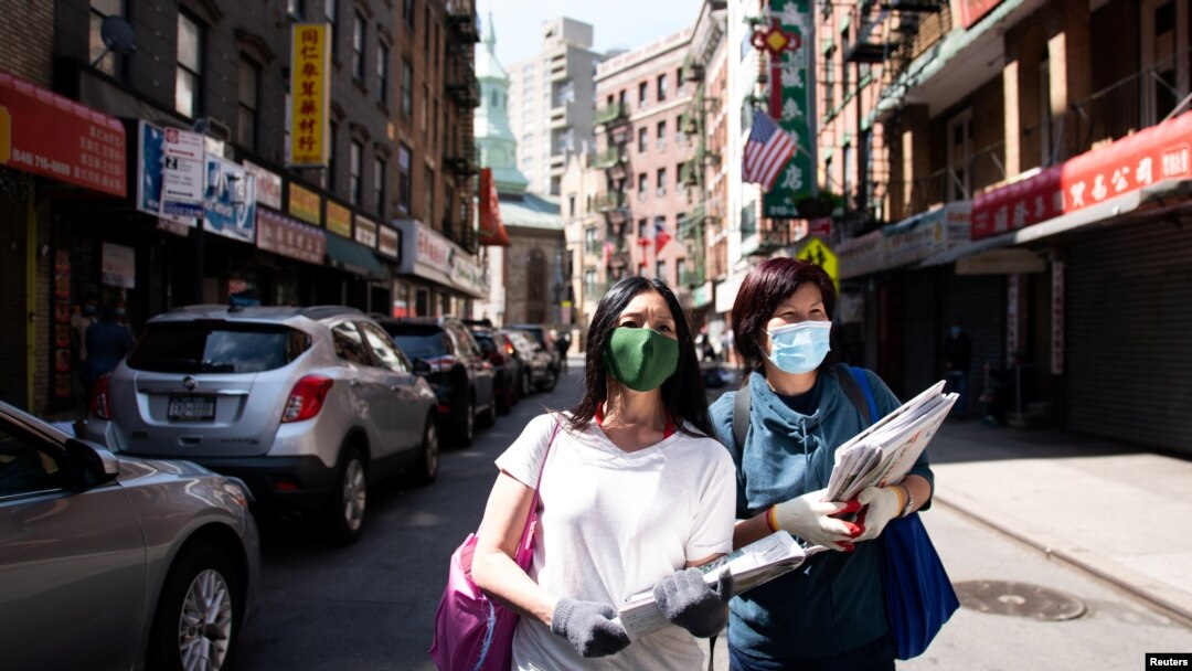 FILE - Shirley Ng (l) , a volunteer with the Chinatown Block Watch neighborhood patrol group, distributes Chinese newspaper along a street in Chinatown during the outbreak of the coronavirus disease (COVID-19) in New York City, New York, May 17, 2020.