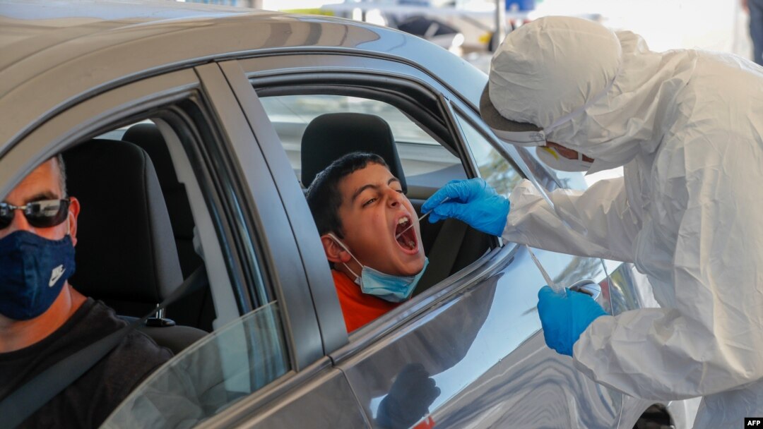 A paramedic with Israel's Magen David Adom (Red Shield of David) national emergency medical service performs a swab test at a drive-thru testing service for COVID-19 coronavirus in Jerusalem, Aug. 27, 2020. 