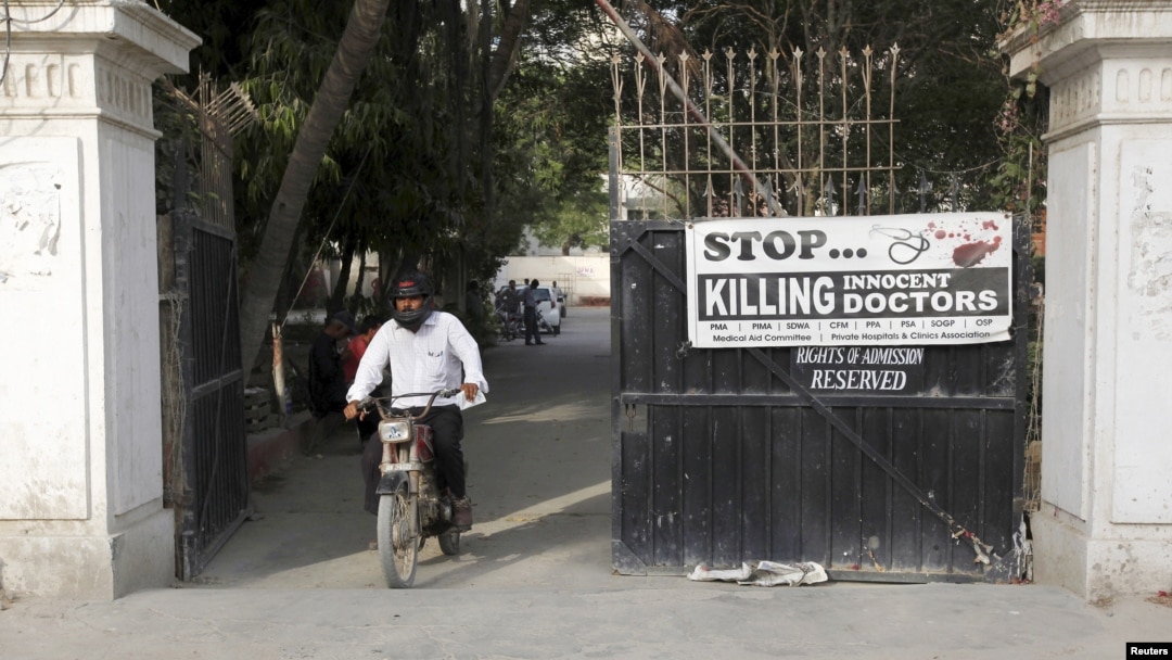 A man rides on a motorbike past a poster installed at the entrance gate of the Pakistan Medical Association office in Karachi, April 8, 2015.