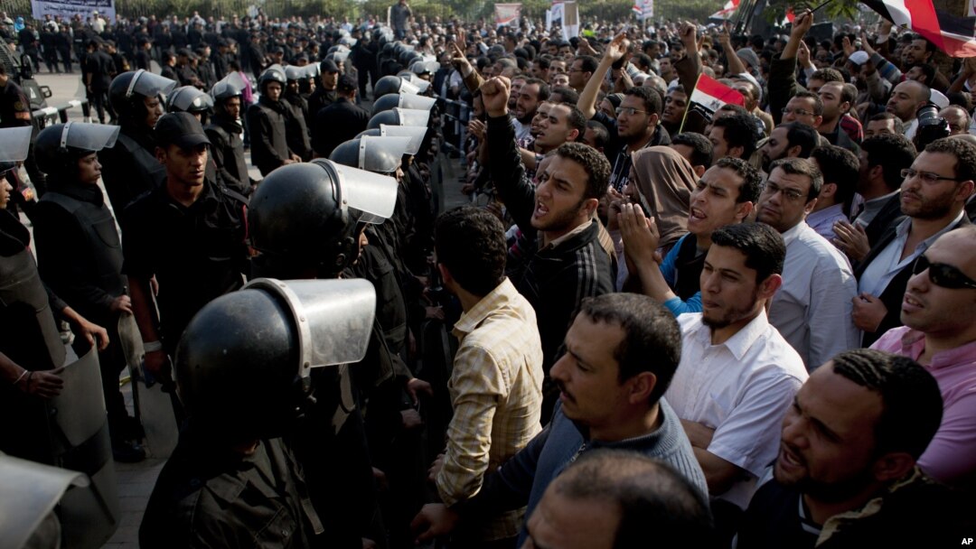 Supporters of Egyptian President Mohammed Morsi chant slogans as riot police, left, stand guard in front of the entrance of Egypt’s top court, in Cairo, Egypt, Sunday, Dec. 2, 2012.