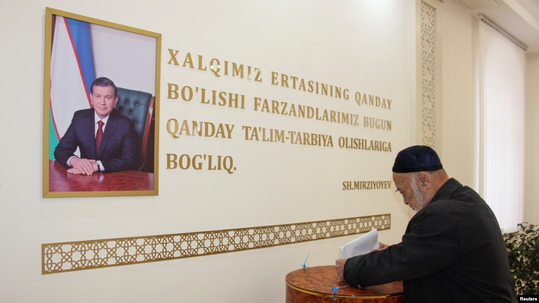 A man casts his ballot next to a portrait of Uzbekistan's President Shavkat Mirziyoyev during parliamentary election in Tashkent, Uzbekistan, Dec. 22, 2019. 