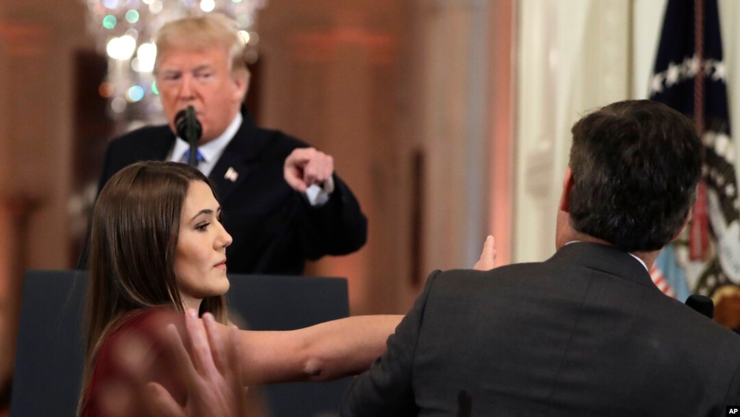 As President Donald Trump points to CNN's Jim Acosta, a White House aide tries to take the microphone from him during a news conference in the East Room of the White House, Nov. 7, 2018, in Washington. 