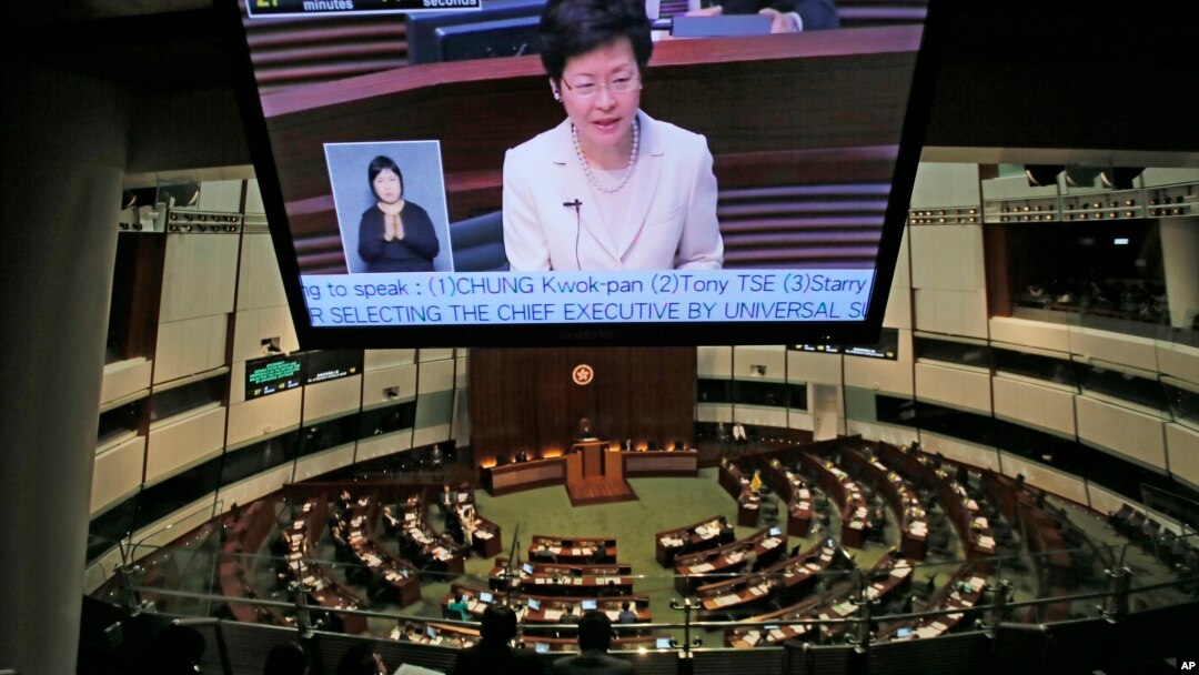 香港政務司司長林鄭月娥在立法會宣讀政改方案聲明,她的影像出現在大型投影機上