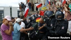 Police officers scuffle with a protester in front of the Reichstag Building during a rally against the government's restrictions following the coronavirus disease (COVID-19) outbreak, in Berlin, Germany, Aug. 29, 2020.