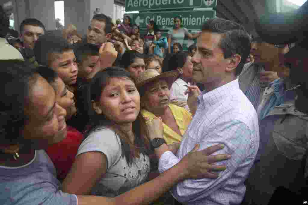 In this photo released by Mexico's presidential press office, Mexican President Enrique Pena Nieto meets with people affected by Tropical Storm Manuel in the Pacific coast city of Acapulco, Mexico, Sept. 16, 2013.