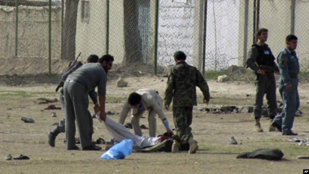 Afghan policemen and security personnel pick up a dead body after a suicide attack at an army recruitment center in Kunduz, March 14, 2011.