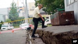 A man walks over ground that shifted in an earthquake in Kiyota, on the outskirts of Sapporo, Hokkaido, northern Japan, Sept. 7, 2018. 