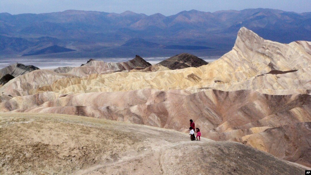 In this April 11, 2010 file photo, tourists walk along a ridge at Death Valley National Park, Calif. Preliminary data show that Death Valley set the world record for hottest month in July 2018.