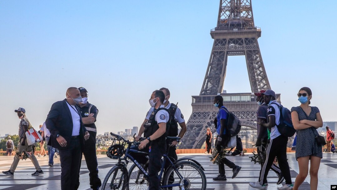 Police officers talk to a man while wearing protective face masks as precaution against the conoravirus at Tocadero plaza near Eiffel Tower in Paris, Sept. 14, 2020.