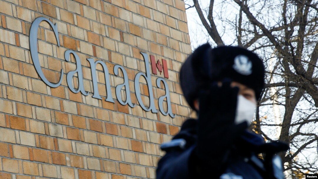 A police officer gestures at the photographer outside the embassy of Canada in Beijing, China, Dec. 12, 2018. 