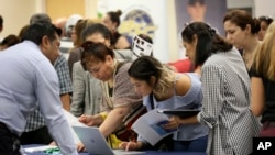 Archivo - Solicitantes buscan empleos disponibles en la sede de la Universidad Internacional de Florida, durante una feria de empleos en Miami.