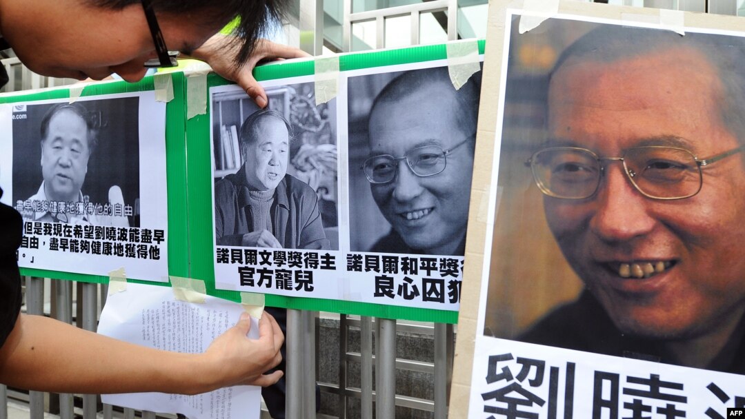 A protester affixes pictures of Chinese writer Mo Yan (L) and Chinese dissident Liu Xiaobo (R) to a gate during a demonstration in front of the Chinese liaison offices demanding the release of Chinese Liu in Hong Kong, October 13, 2012. 