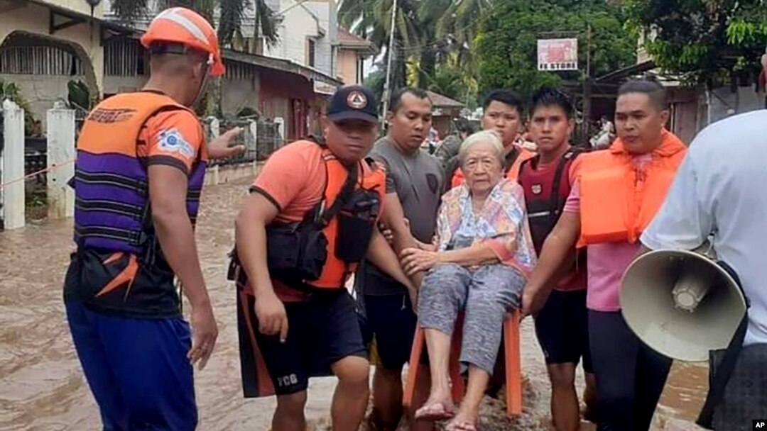 En esta imagen proporcionada por la Guardia Costera de las Filipinas, una anciana es transportada sobre una silla por personal del servicio de guardacostas en medio de una inundación, el lunes 26 de diciembre de 2022, en Plaridel, en el sur de las Filipinas. 
