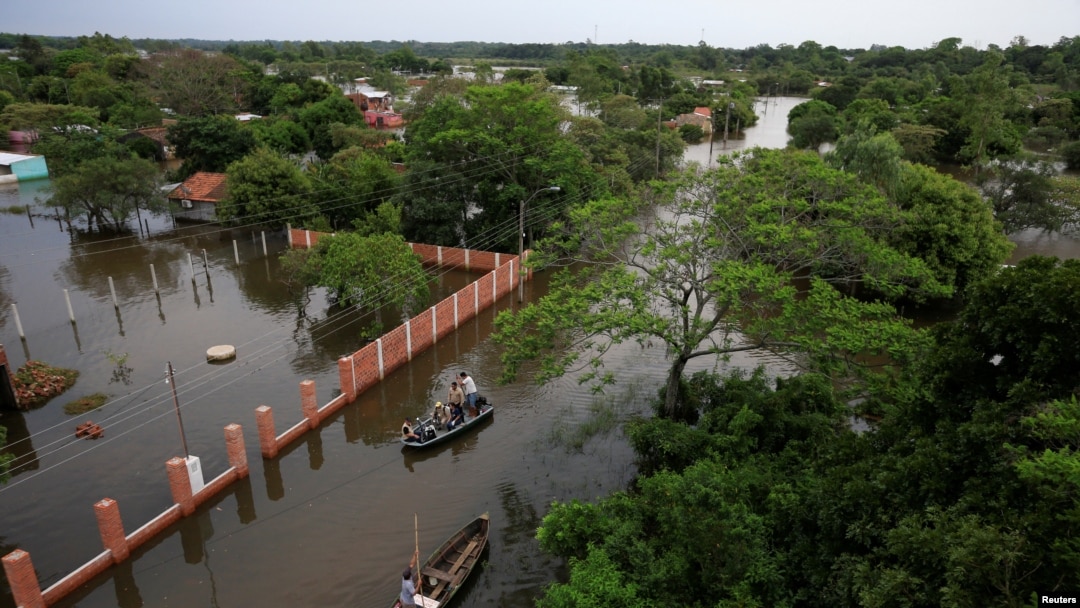 La gente viaja en botes en un área inundada después de que el río Paraná se desbordó debido a las fuertes lluvias, en Ayolas, Paraguay, 8 de noviembre de 2023.