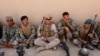 FILE - A U.S. Marine, center, talks with Afghan National Army soldiers during a training in Helmand province, Afghanistan, July 5, 2017.