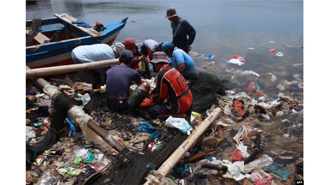 FILE - Fishermen sort their catch from a net as they fish in polluted waters filled with plastic waste in Bandar Lampung, Feb. 21, 2022.
