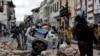 Un policía junto a un automóvil aplastado por los escombros después de que un terremoto sacudiera Cuenca, Ecuador, el sábado 18 de marzo de 2023. (AP Foto/Xavier Caivinagua)