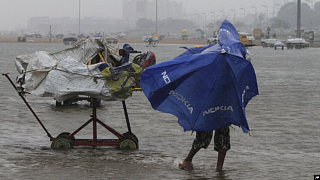 A boy struggles to hold onto his umbrella during strong winds on Marina beach in the southern Indian city of Chennai, December 29, 2011.