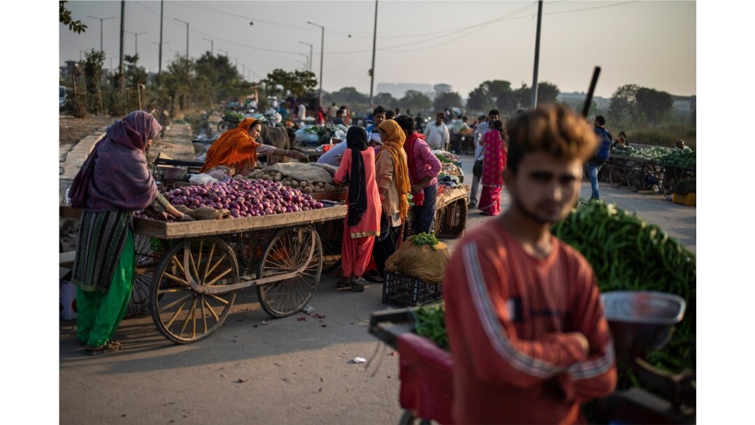 FILE - Vendors and customers are seen without masks at a market on the outskirts of New Delhi, India, Nov. 20, 2020.