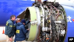 National Transportation Safety Board investigators examine damage to the engine of the Southwest Airlines plane that made an emergency landing at Philadelphia International Airport in Philadelphia, April 17, 2018.