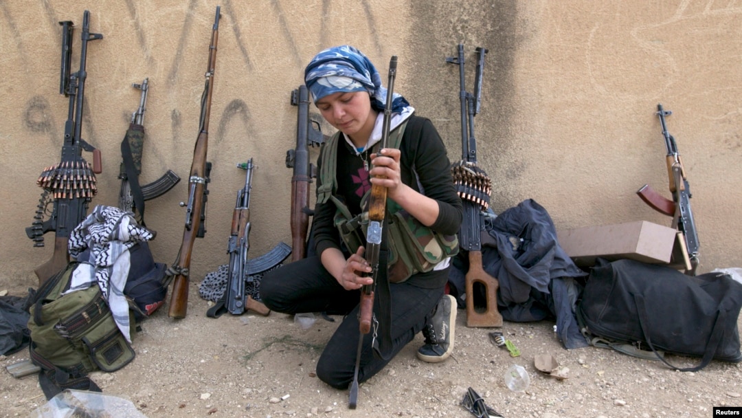 FILE - A female Kurdish fighter from Kurdish People's Protection Units (YPG) checks her weapon near Ras al-Ain, in the Syrian province of Hasakah, after capturing it from Islamist rebels November 6, 2013. 